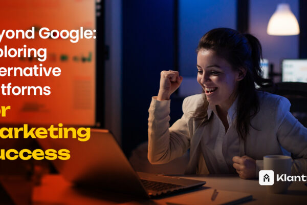 A woman celebrates a marketing win at her desk, smiling with a raised fist while looking at her laptop in a modern, dim-lit workspace.