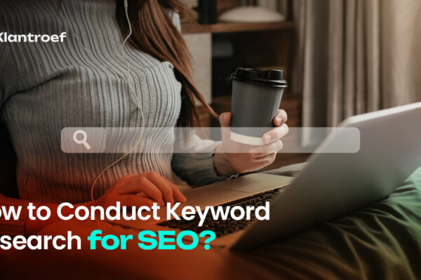 A woman sitting on a couch with a laptop and coffee cup, conducting keyword research online.