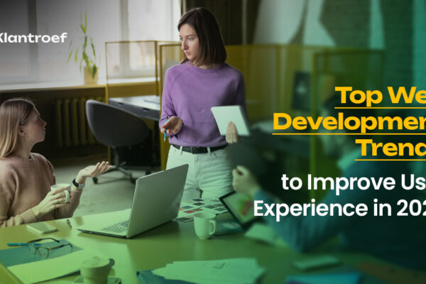 Three professionals are discussing ideas in a modern workspace with laptops and documents on the table. The text reads “Top Web Development Trends to Improve User Experience in 2025” with Klantroef branding.